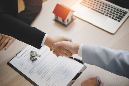 Close up of real estate agent shaking hands with client after signing contract.