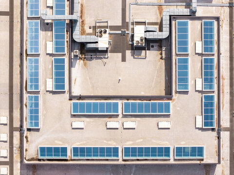 Aerial view of a shopping center rooftop featuring numerous rectangular skylights, ventilation units, and industrial ductwork in Warsaw, Masovian Voivodeship, Poland.