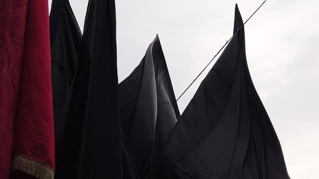 Black and Red Mourning Flags Waving
in Wind Against Cloudy Sky on Ashura
in Karbala