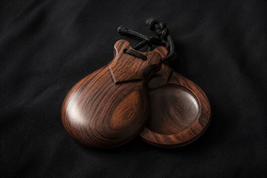 Traditional flamenco castanets resting on dark textured fabric.