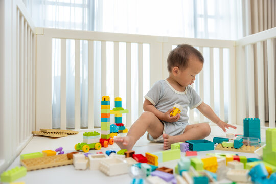 Toddler playing with blocks in safe playpen