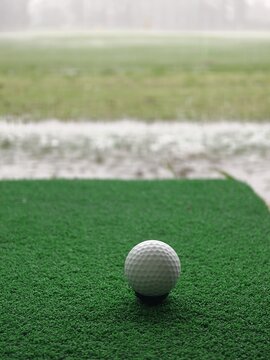 White Golf Ball Resting on a Black Tee on Artificial Turf