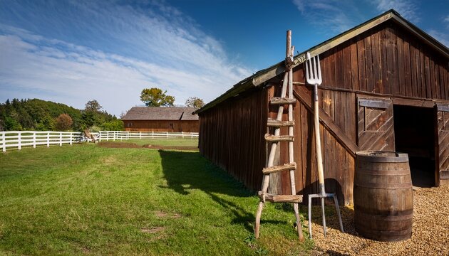 charming farmyard view with ladder leaning on barn and barrel beside pitchfork