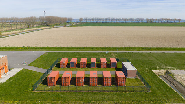 Aerial view of a fenced compound with rows of red shipping containers situated in a rural landscape near Middelharnis, South Holland, Netherlands.