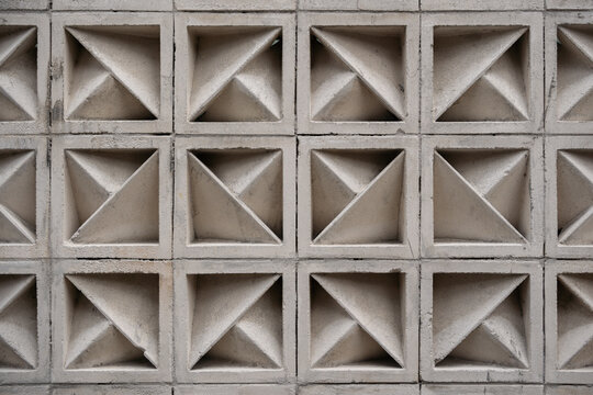Close up of light grey concrete breeze blocks forming a repeating geometric 3D pattern for architectural textures.