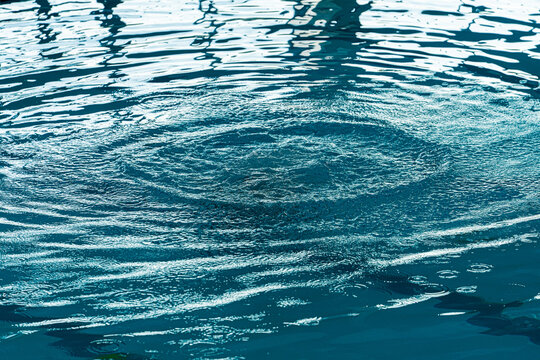 Concentric water ripples abstract background from an impact on a blue liquid surface