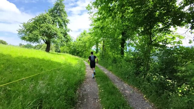 A trail runner follows natural paths through open meadows beneath a clear blue sky with views of Rigi and the Central Swiss mountains. Enjoying solitude, nature, and outdoor adventure in Switzerland.