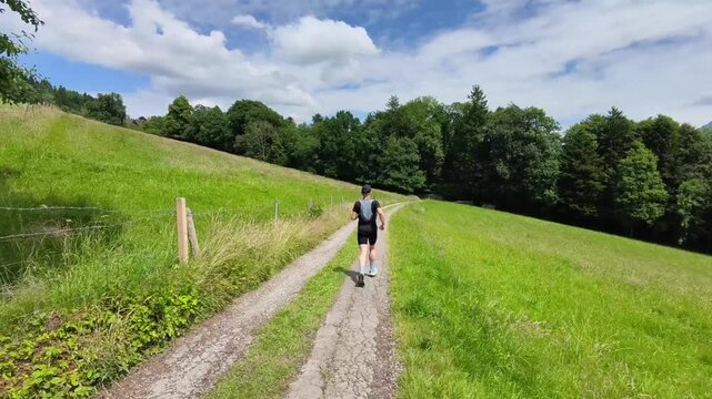 A trail runner follows natural paths through open meadows beneath a clear blue sky with views of Rigi and the Central Swiss mountains. Enjoying solitude, nature, and outdoor adventure in Switzerland.