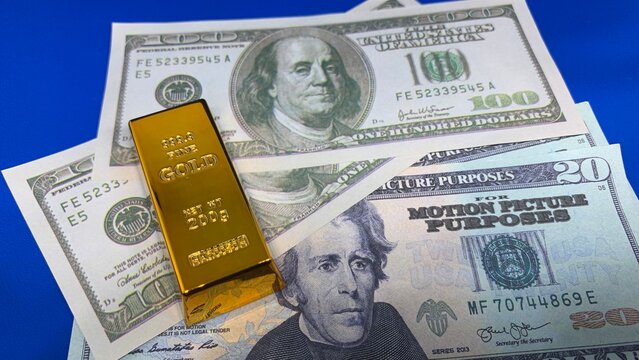 Gold bar positioned on U.S. dollar bills, symbolizing wealth, investment value, and financial security concepts