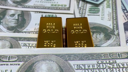wo gold bars positioned on U.S. hundred-dollar bills, emphasizing wealth storage, investment value, and financial stability concepts © MR HEPPY