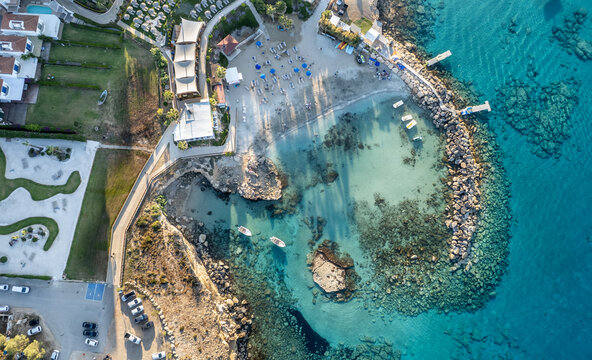 Drone seascape of loumbardi isolated beach bay featuring a luxury resort, sandy beach, sun loungers, and crystal clear turquoise water. Protaras, Cyprus