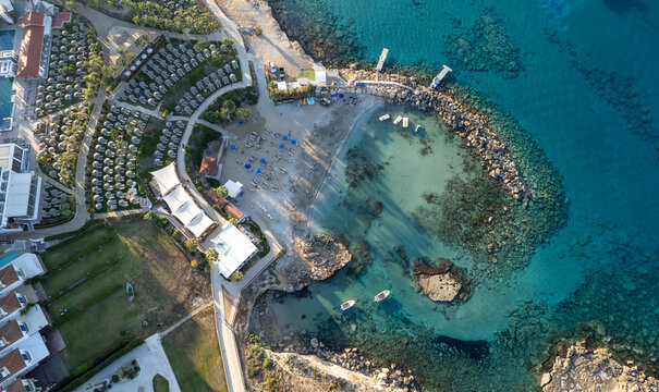 Drone seascape of loumbardi isolated beach bay featuring a luxury resort, sandy beach, sun loungers, and crystal clear turquoise water. Protaras, Cyprus