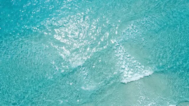 Ocean water surface sunlight reflections gentle waves turquoise blue sea nature sparkling white foam clear tropical beach aerial view summer vacation background