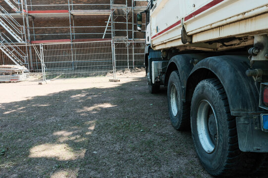 Construction site with a truck parked near scaffolding and building materials under a clear sky during the day