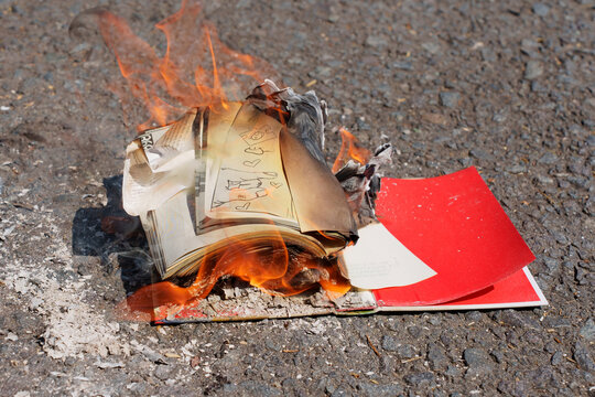 Book With Red Cover Burning On Asphalt Ground