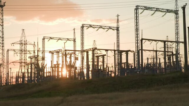 Exterior view of high voltage transformer substation against background of sunset sky