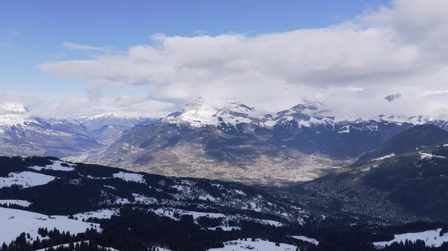 Wide panoramic aerial view of the snow-covered Alps in winter, showing the valleys and mountains around Sallanches, Passy, and the Mont Blanc massif in the French Alps. The landscape features