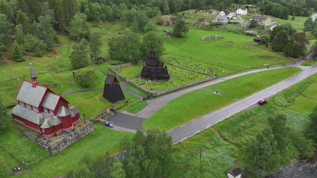 Aerial drone flyover of Borgund Stave Church with river and visitor centre in background, Norway