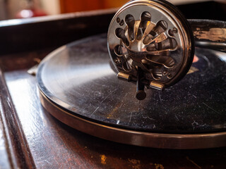 Obraz premium Macro close-up of a vintage gramophone soundbox and needle resting on a record. Antique analog music player with polished metal tonearm, showcasing early audio technology and craftsmanship.