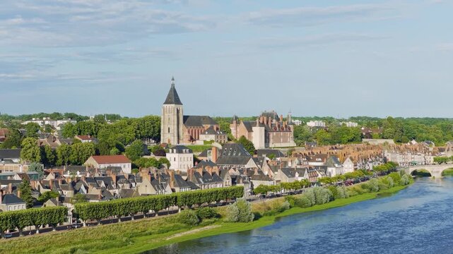 Aerial footage of the picturesque town of Gien in central France, featuring the historic Gien Castle, a prominent church, traditional French rooftops, and the Loire River with a stone bridge. The