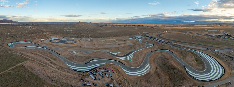 Aerial view of Willow Springs International Raceway, showing the winding asphalt track with green and white curbing, in the arid desert of Rosamond, California, United States.