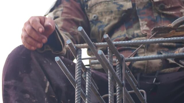 Construction worker builder welding rebar steel reinforcement in building works at site with industry concept in 4K Ultra HD footage.
