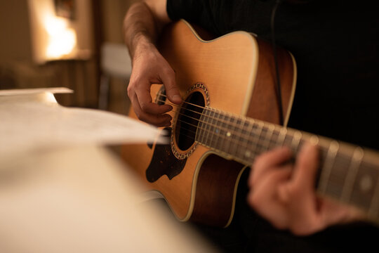 Cropped male musician playing guitar near table. Man creating music