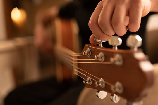 Cropped guitarist tuning instrument during rehearsal