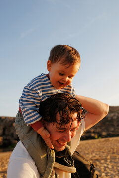 Smiling Toddler on Dad's Shoulders at the Beach