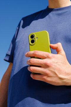 Businessman Holding Smartphone Outdoors Against Blue Sky