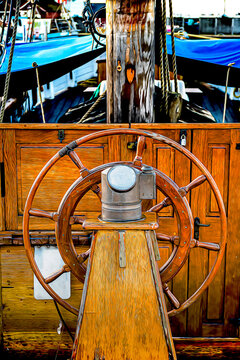The wooden ship's steering wheel at the stern of a sailing ship, depicted as a cartoon illustration.