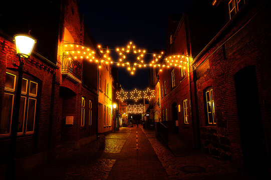 The Schlo&szlig;gang street in Husum at night during the Christmas season, depicted as a cartoon illustration.
