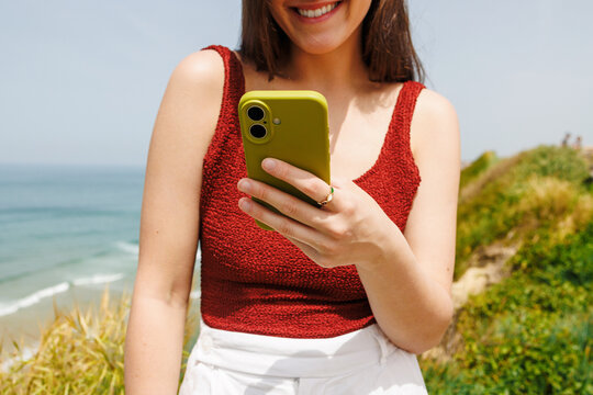 Woman Traveling with Phone by Ocean Cliffs