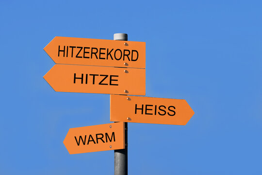 Schilder vor einem blauen Himmel mit der Aufschrift warm, hei&szlig;, Hitze und Hitzerekord