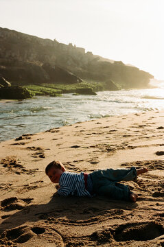 Child lying on sandy beach near water film photo