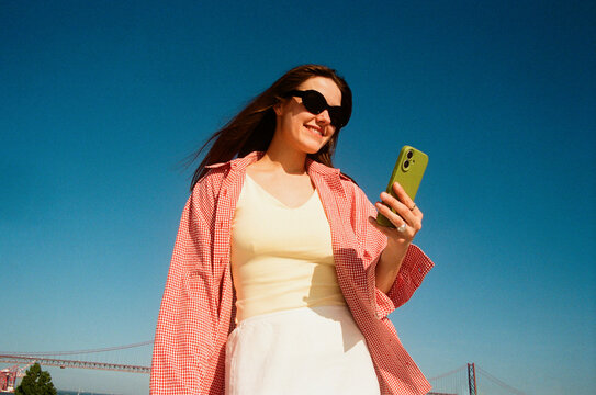 Woman using smartphone outdoors blue sky film photo
