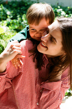 Child hugging mom outdoors in sunlight film photo