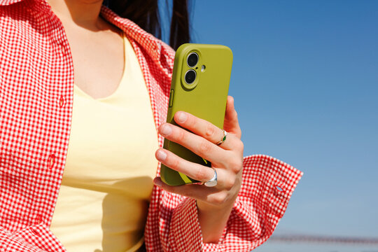 Woman holding green smartphone outdoors in sunlight