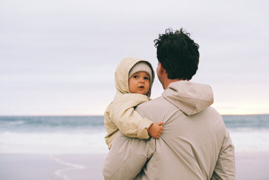 Man holding child by ocean at sunset film photo