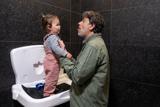 Father And Toddler Sharing Funny Moment During Diaper Change