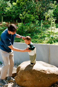 Man helping child on rock outdoors film photo