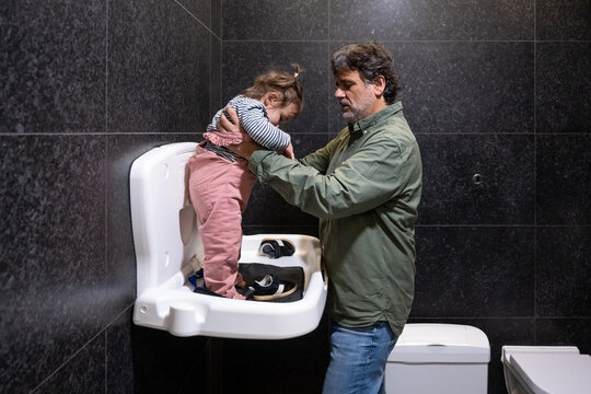 Father Lifting Toddler From Public Changing Station
