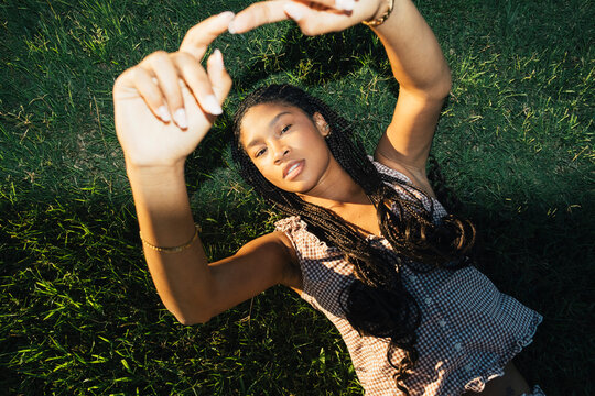 Young woman posing on grass with hands framing face in flash portrait