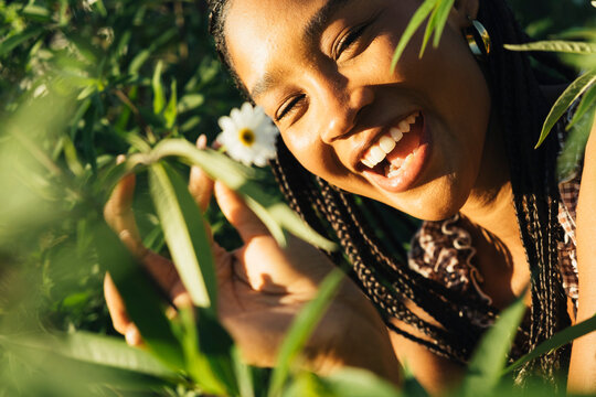Young woman surrounded by greenery in warm evening light