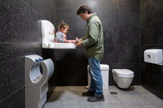 Father Changing Baby Diaper In Public Restroom Changing Station