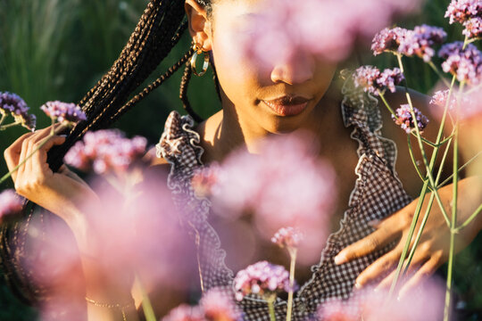 Young woman framed by pink flowers in dreamy outdoor portrait