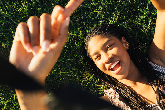 Young woman posing on grass with hands framing face in 