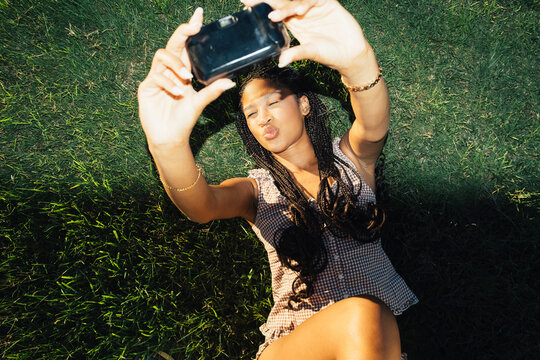 Young woman holding camera above face in playful flash portrait