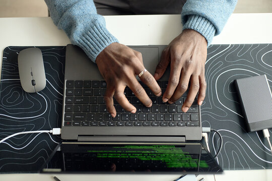 Overhead shot of young adult man typing on laptop, working on digital task at desk. Ideal for office work, cybersecurity, data management, productivity themes