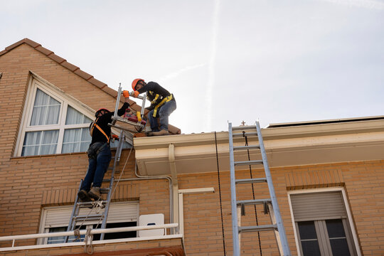 Construction workers installing roof on building exterior